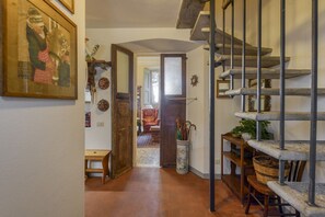 A hallway with a wooden bench, a door leading to another room, a staircase, and a wall-mounted shelf with baskets. - VARESE - Old-time villa next to golf course (Varese)
