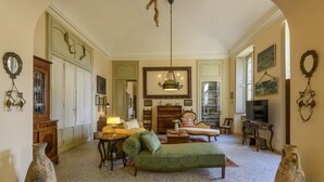 Ein geräumiges Wohnzimmer mit einem grünen Sofa, Holzmöbeln, einer Chandelierleuchtre und einem Fernseher.