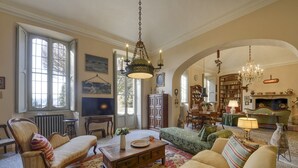 Ein geräumiges Wohnzimmer mit Kamin, Bücherregalen und einer Chandelier.