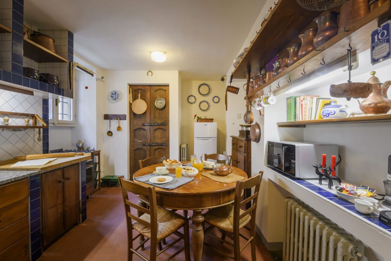 A kitchen with a dining table, chairs, a refrigerator, and a microwave.