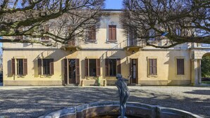 Ein Innenhof mit einer Fontäne und einer Statue, umgeben von einem Gebäude mit zahlreichen Fenstern und Eingängen.