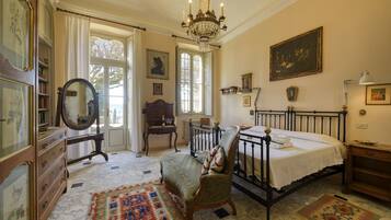 Une chambre à coucher comprenant un lit, une chaise, une commode, un miroir et un lustre.