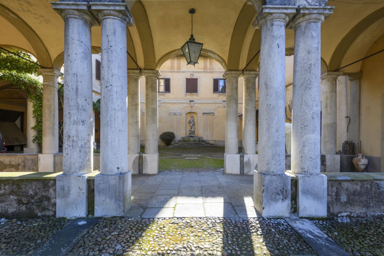 A courtyard with columns, a statue, and a building in the background.