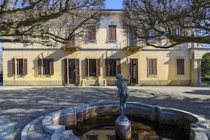 A courtyard with a fountain and a statue, surrounded by a building with multiple windows and doors. - VARESE - Old-time villa next to golf course (Varese)