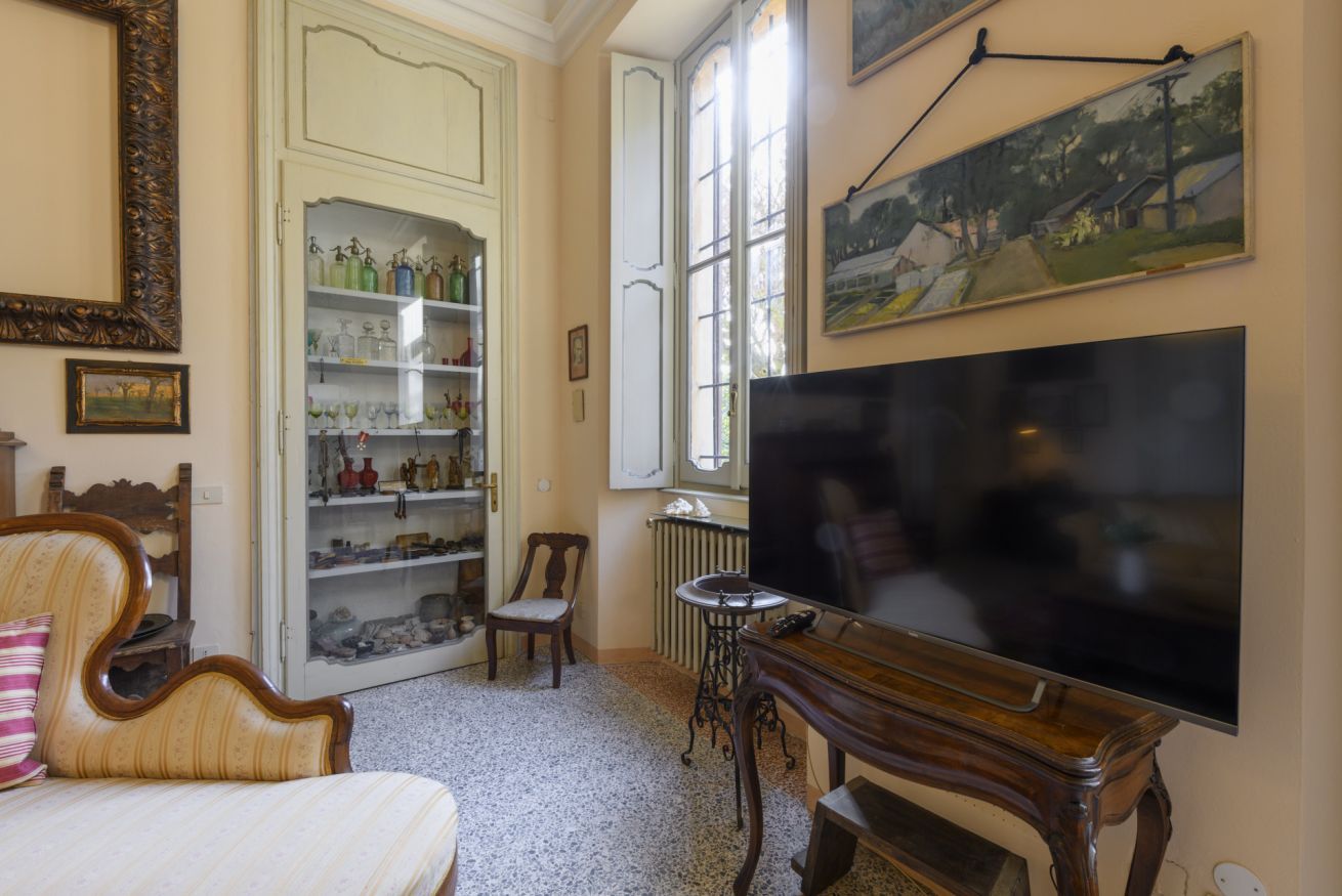 A living room with a television, a bookshelf, a chair, and a window.