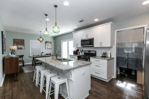 A modern kitchen with white cabinets, a granite countertop, and a stainless steel refrigerator. - Stylish Cottage Near Stadium, BeltLine & Downtown (Atlanta)