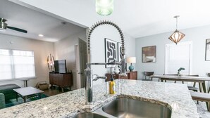 Eine moderne Küche mit einer Granitabdeckung, einer Edelstahl-Spüle und einem ungewöhnlichen, gebogenen Wasserhahn.