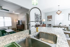 A modern kitchen with a granite countertop, stainless steel sink, and a unique curved faucet. - Stylish Cottage Near Stadium, BeltLine & Downtown (Atlanta)