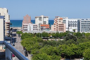Un paisaje urbano costero con edificios de varios pisos, cielo despejado y vista al mar.