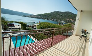 Un balcon avec piscine, donnant sur un lac et des collines.