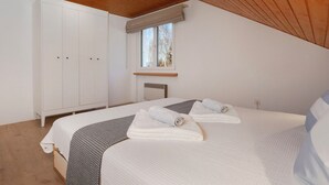 A bedroom with a bed, a wardrobe, a window, and a ceiling light.
