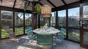 A modern dining area with a round table, striped chairs, and a hanging plant.