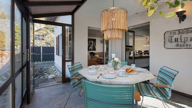 A dining area with a round table, striped chairs, and a hanging light fixture.