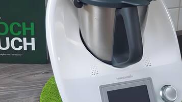 A kitchen appliance with a digital display, a control knob, and a stainless steel pot.