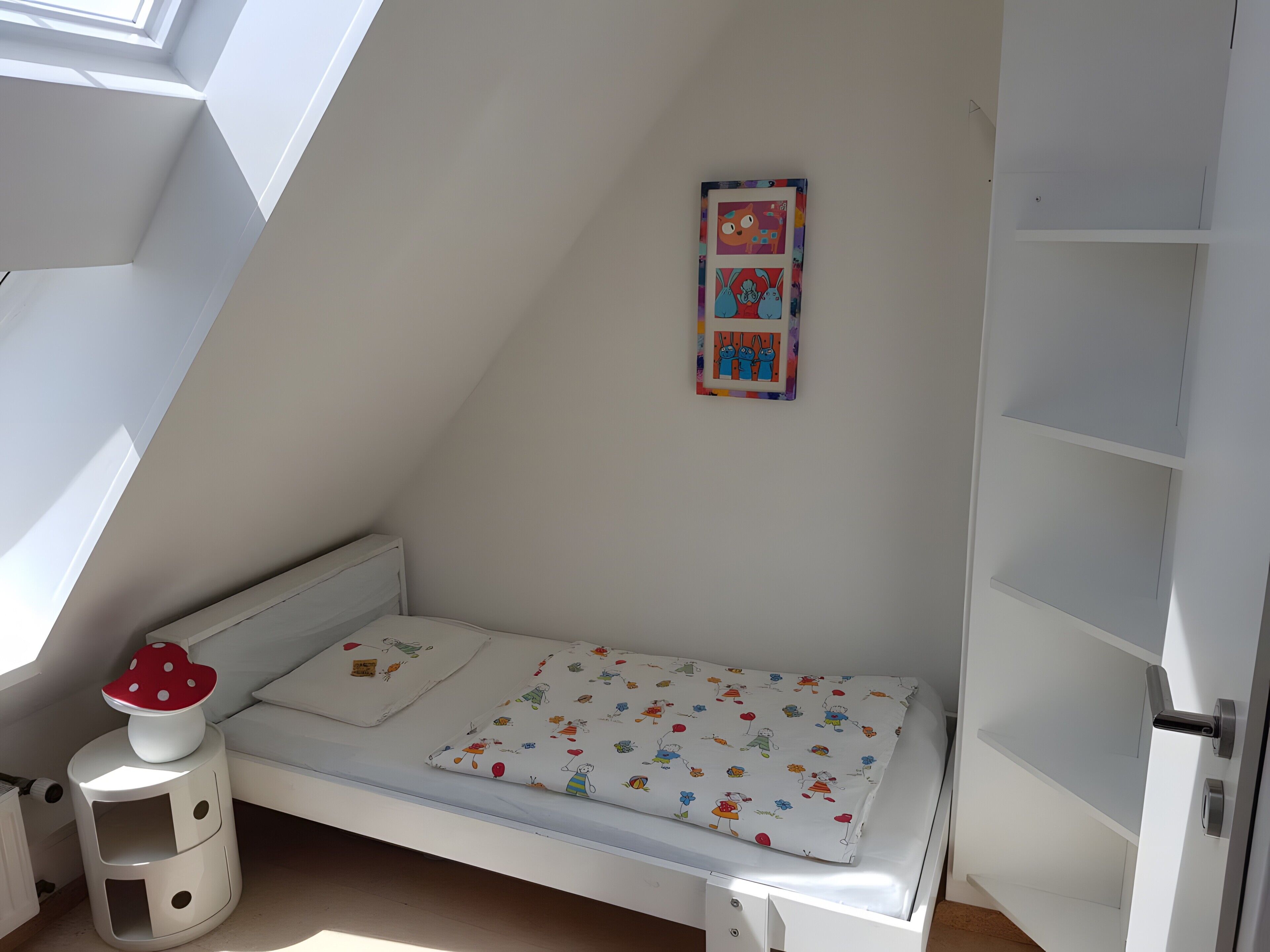 Een kinderstapelbed met een kleurrijk matras, een klein krukje en een aan de muur bevestigd fotolijstje.