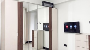A modern bedroom with a wardrobe, a television, and a mirror. - Charming 1-bedroom apartment with AC, Power backup  and Dishwasher in  Kampala (Kampala)