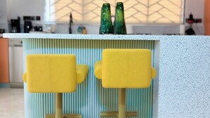 A modern kitchen with two yellow bar stools, a white countertop, and a decorative backsplash. - Charming 1-bedroom apartment with AC, Power backup  and Dishwasher in  Kampala (Kampala)