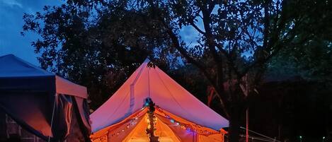 Un área de camping con carpas, un hoyo para fuego y sillones.