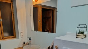 A bathroom with a wooden vanity, a sink, a mirror, and a towel rack.