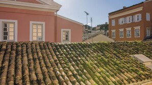 Un edificio con techo de tejas de terracota, marcos de ventana blancos y cielo despejado.