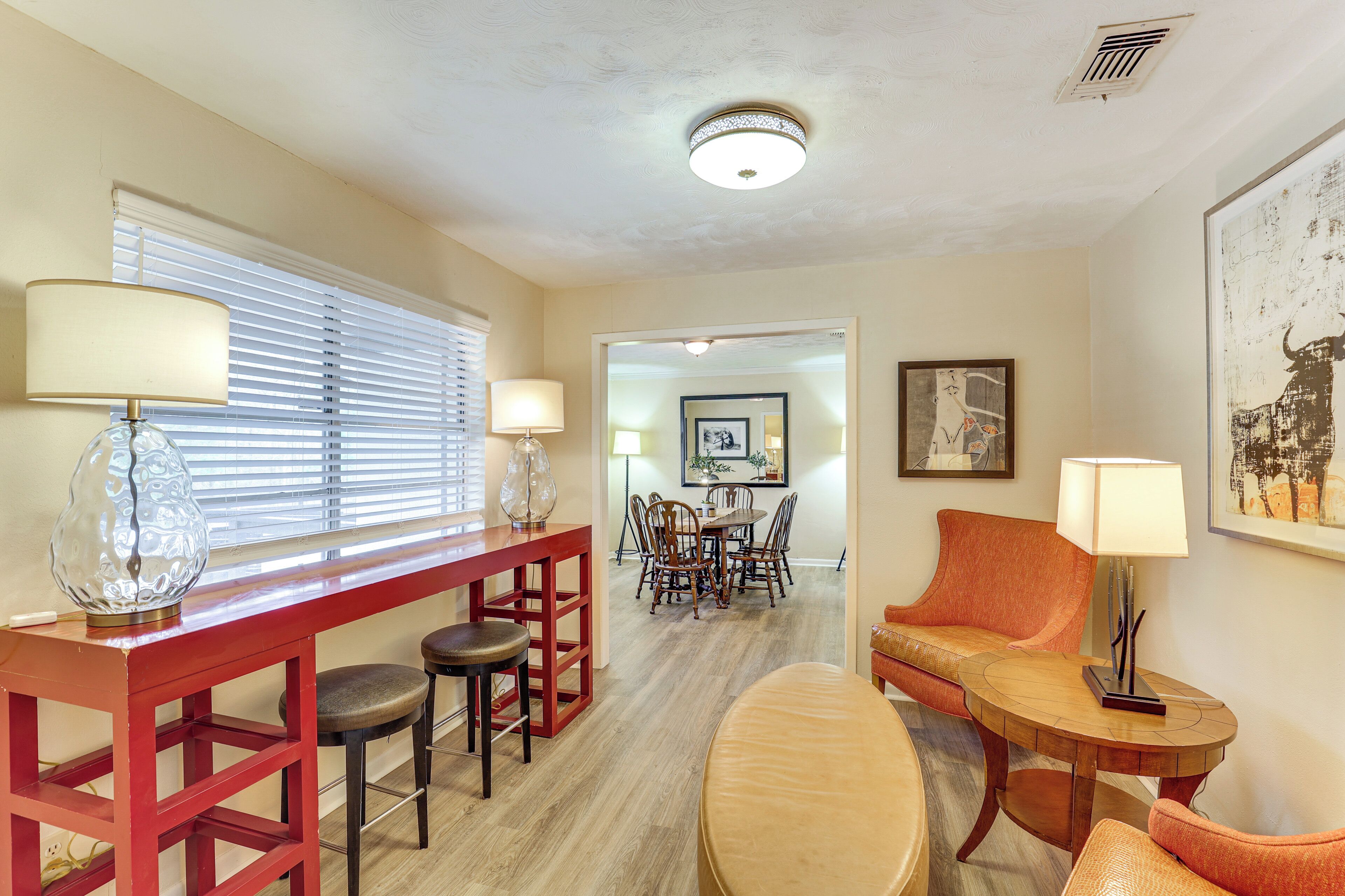 A dining area with a red table and chairs, a sofa, and a lamp.