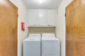 A laundry room with two white washers and dryers, wooden doors, and a red fire extinguisher on the wall. - Hike, Fish & Swim: Nat'l Forest Home in Crockett (Kennard)