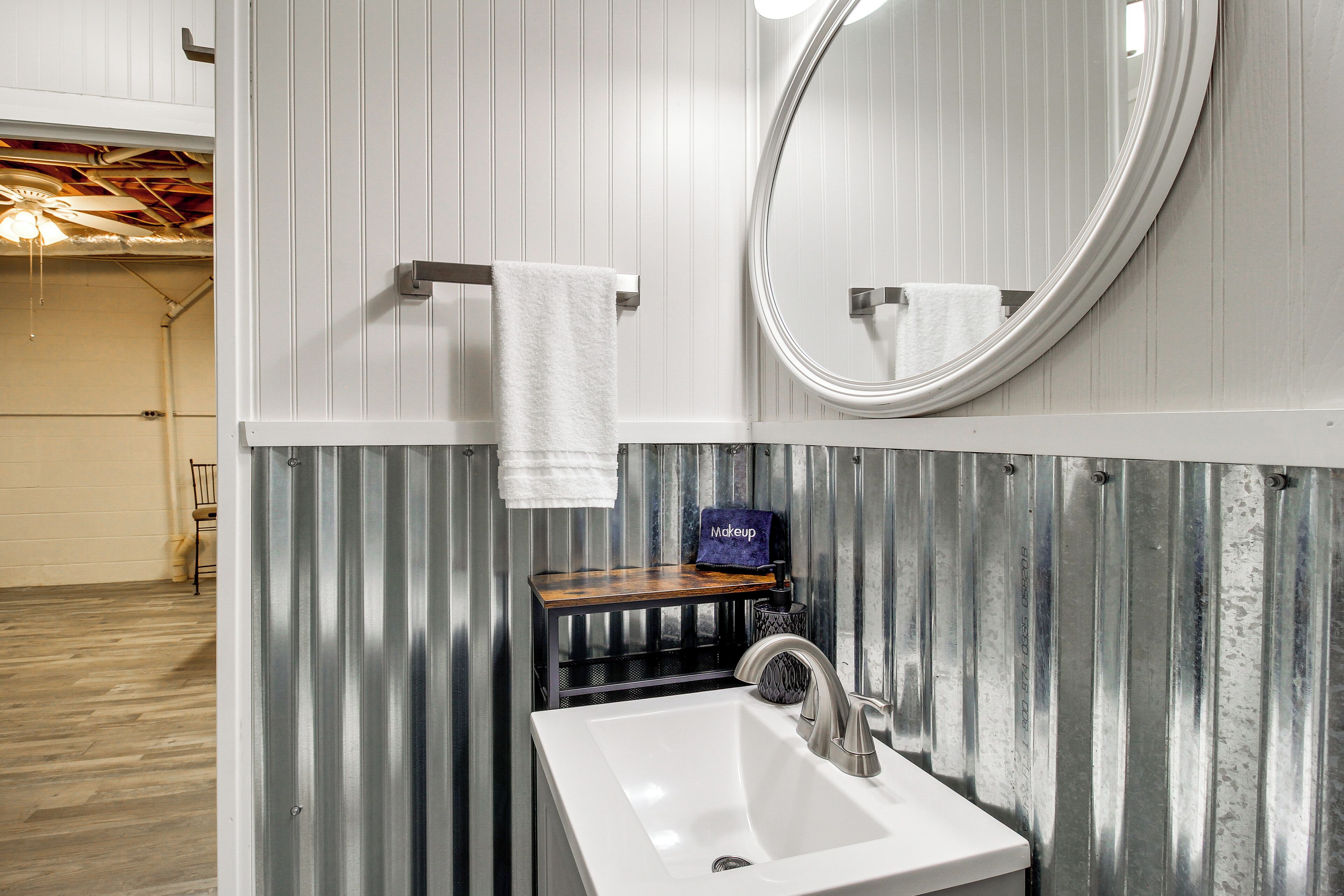 A bathroom with a white sink, a round mirror, and a towel rack.