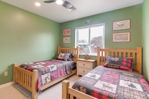 A bedroom with two wooden beds, a nightstand, and a window with a view.