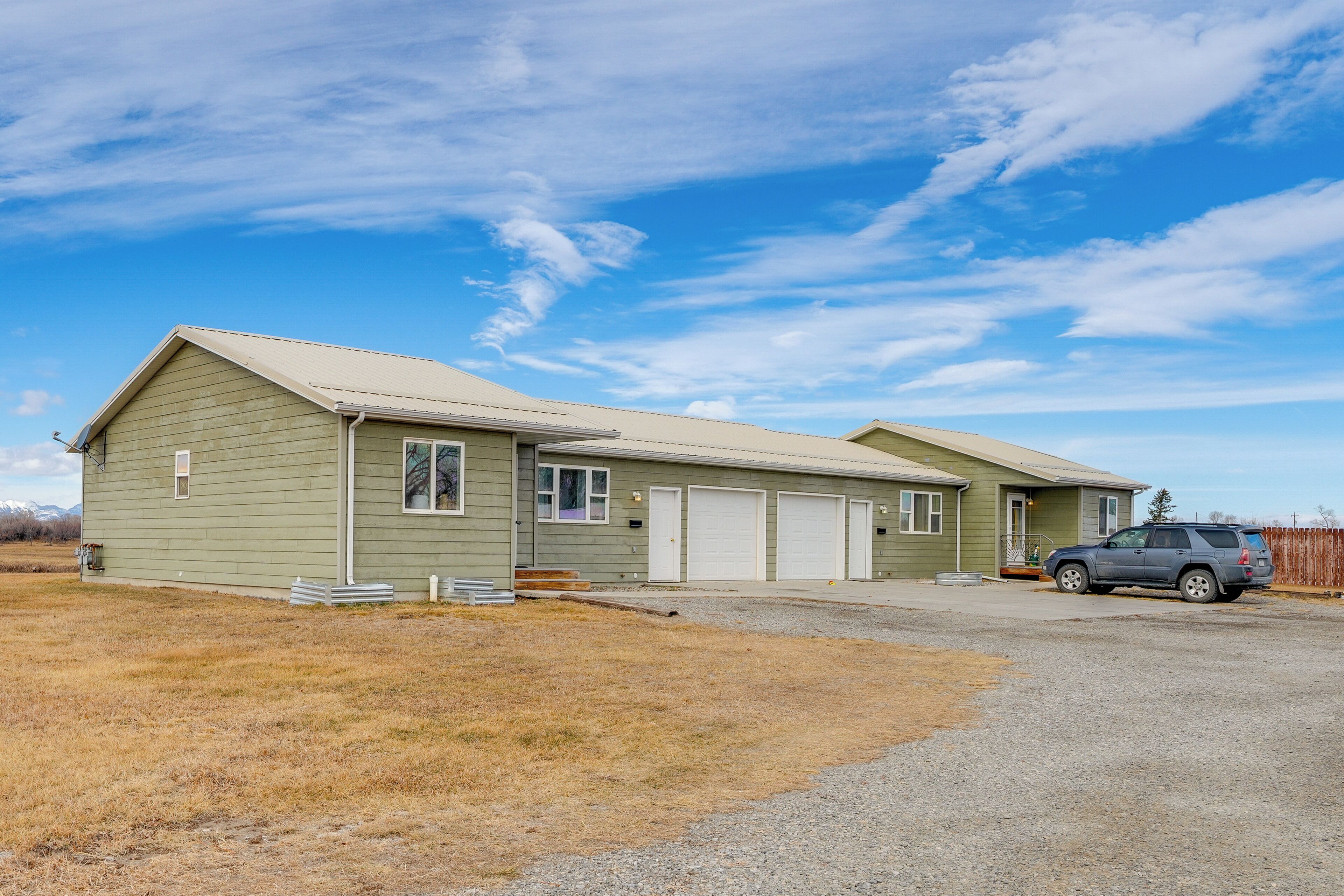 A single-story house with a garage, a driveway, and a parked SUV.