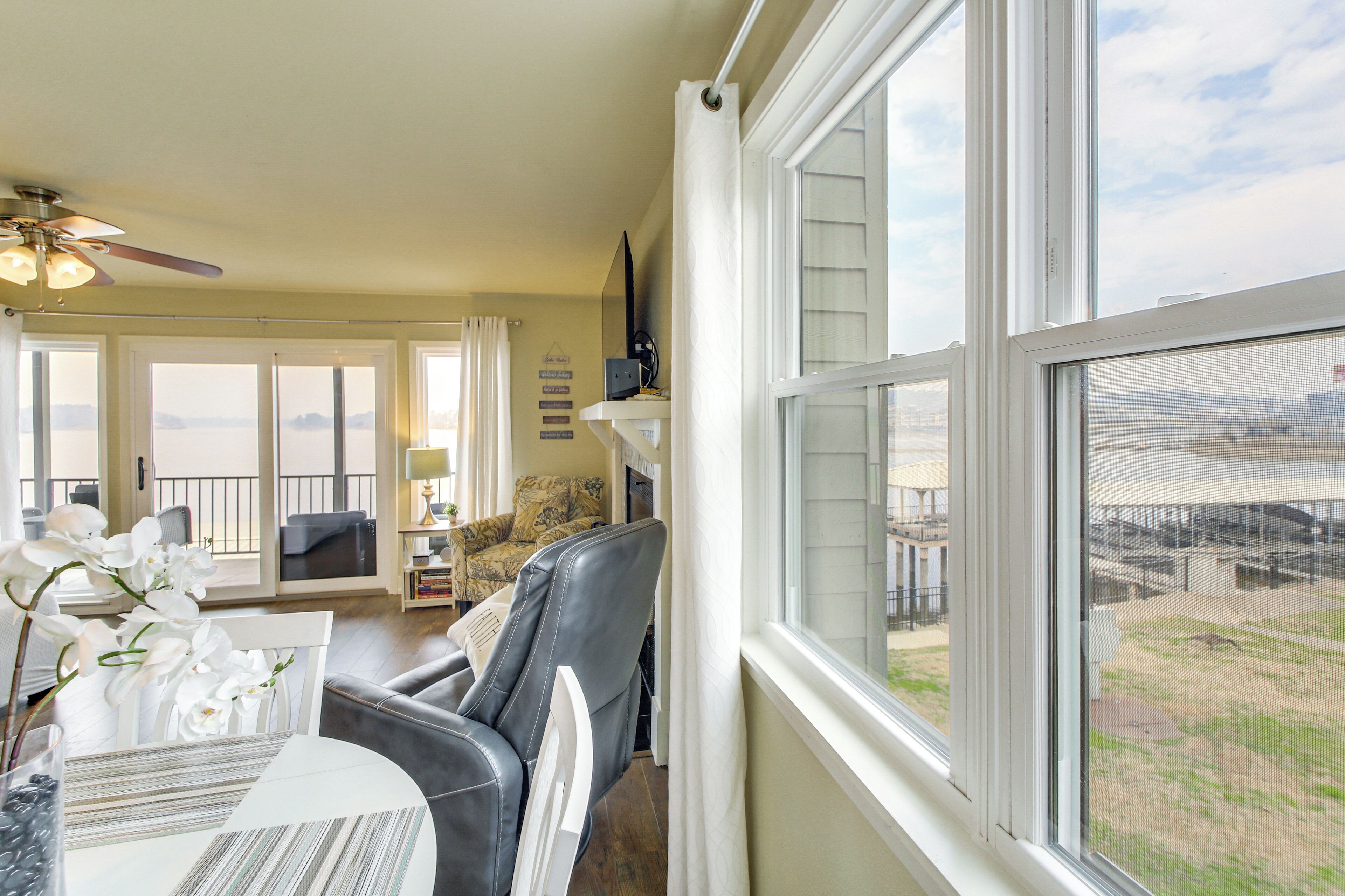 A spacious living room with a large window, a ceiling fan, and a view of the outdoors.