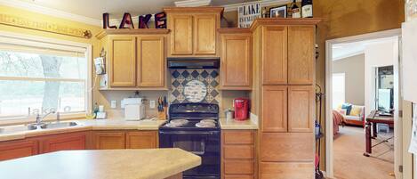A kitchen with wooden cabinets, a stove, and a refrigerator.