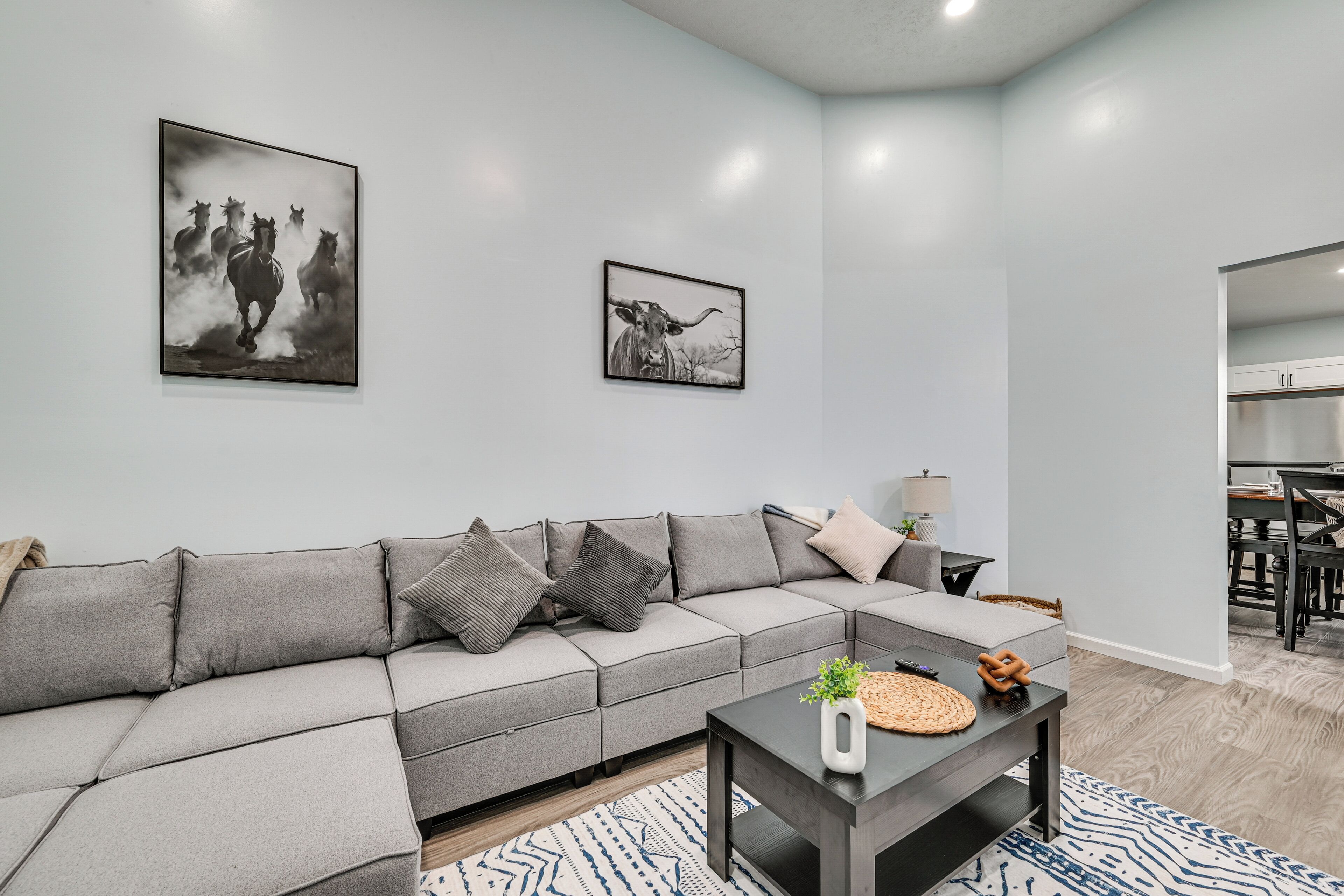 A modern living room with a grey sectional sofa, a coffee table, and two framed pictures on the wall.