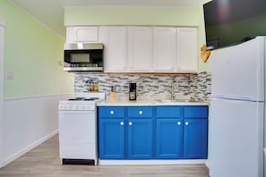 A kitchen with white cabinets, a blue countertop, a white refrigerator, and a stove. - Peace & Relaxation at Texas Countryside Tiny Home (Bowie)