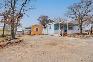 A two-story house with a porch and a fenced yard. - Peace & Relaxation at Texas Countryside Tiny Home (Bowie)