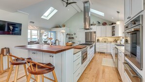 A modern kitchen with a central island, bar stools, a large stove, and a ceiling fan. - < 1 Mi to Port Clyde Village: Modern Retreat (Tenants Harbor)