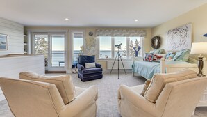 A spacious room with a large window, a blue chair, a bed, and a tripod. - < 1 Mi to Port Clyde Village: Modern Retreat (Tenants Harbor)