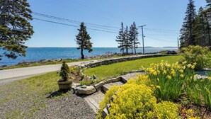 A coastal road with a stone pathway, yellow flowers, and evergreen trees. - < 1 Mi to Port Clyde Village: Modern Retreat (Tenants Harbor)