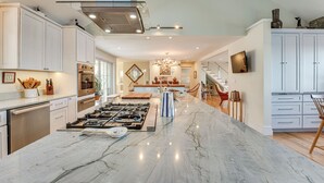 A spacious kitchen with a large island, modern appliances, and a dining area with a chandelier. - < 1 Mi to Port Clyde Village: Modern Retreat (Tenants Harbor)