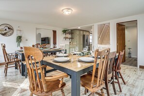 Een eetgedeelte met een houten tafel gedekt voor zes personen, omringd door houten stoelen.