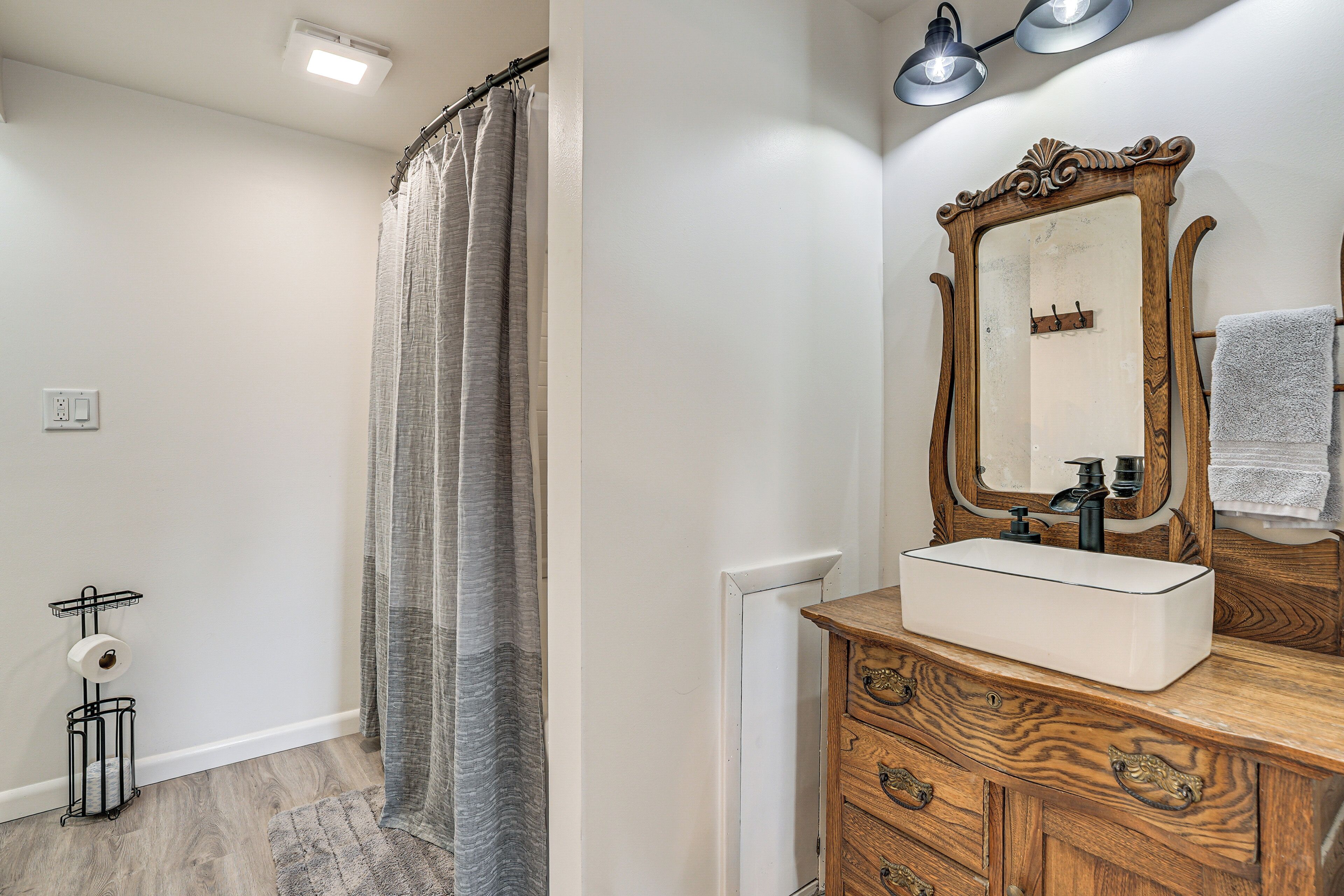 A bathroom with a wooden vanity, a mirror, and a shower curtain.