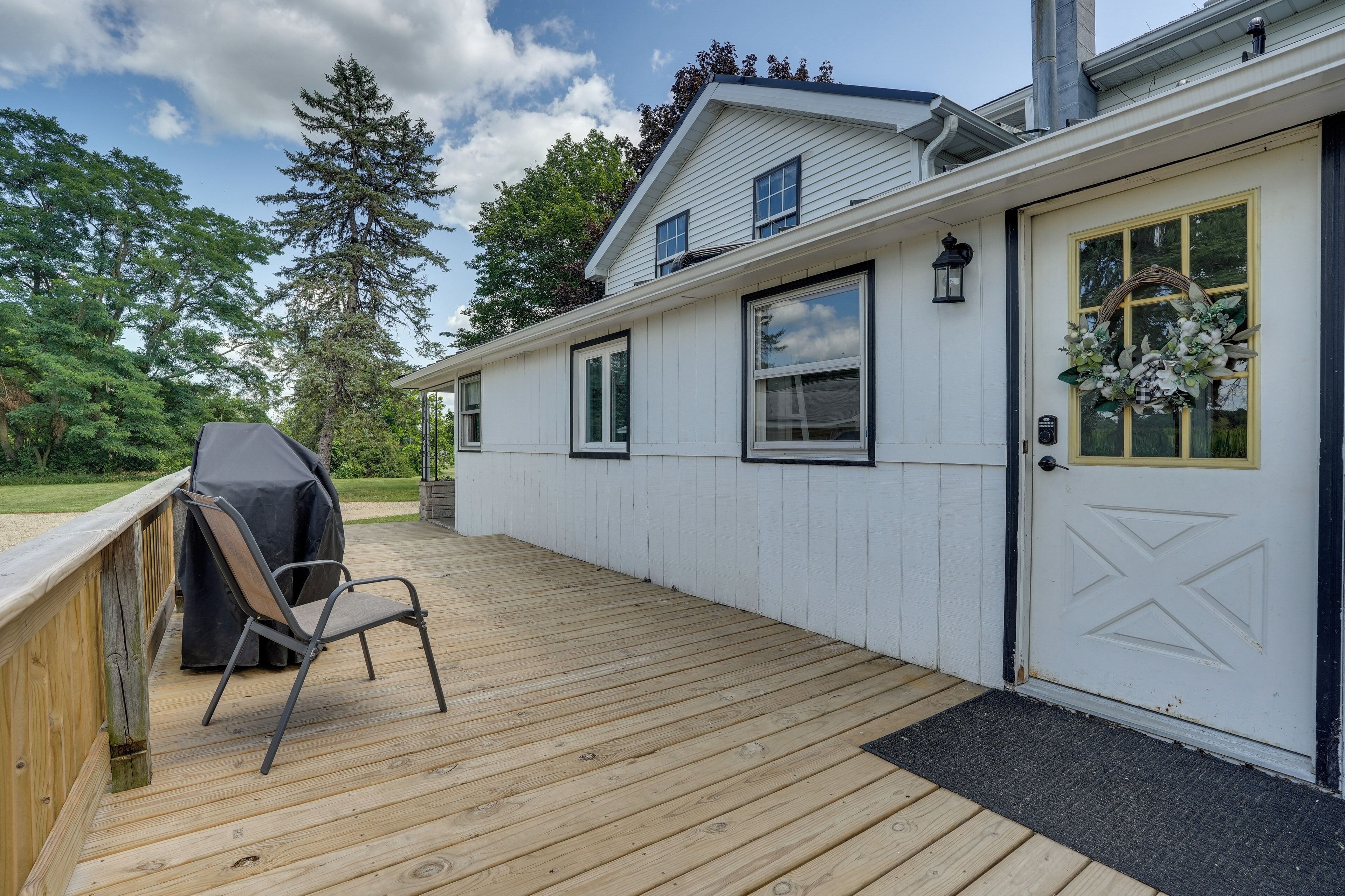 Ein Haus mit einer Terrasse, einem Grill und einer Türkranz-Dekoration.
