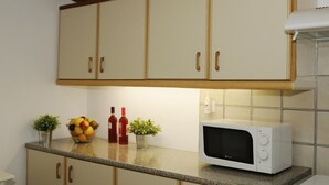 Een keuken met houten kastjes, een magnetron, een schaal met fruit en twee bloempotten.