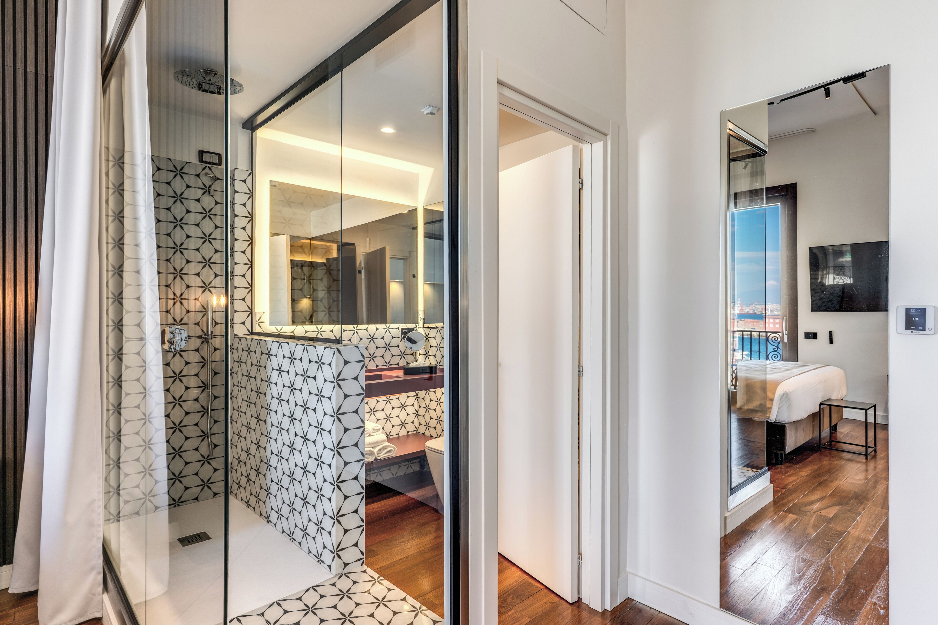 A modern bathroom with a geometric tile pattern, a glass shower enclosure, and a visible toilet.