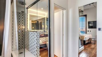 A modern bathroom with a geometric tile pattern, a glass shower enclosure, and a visible toilet.