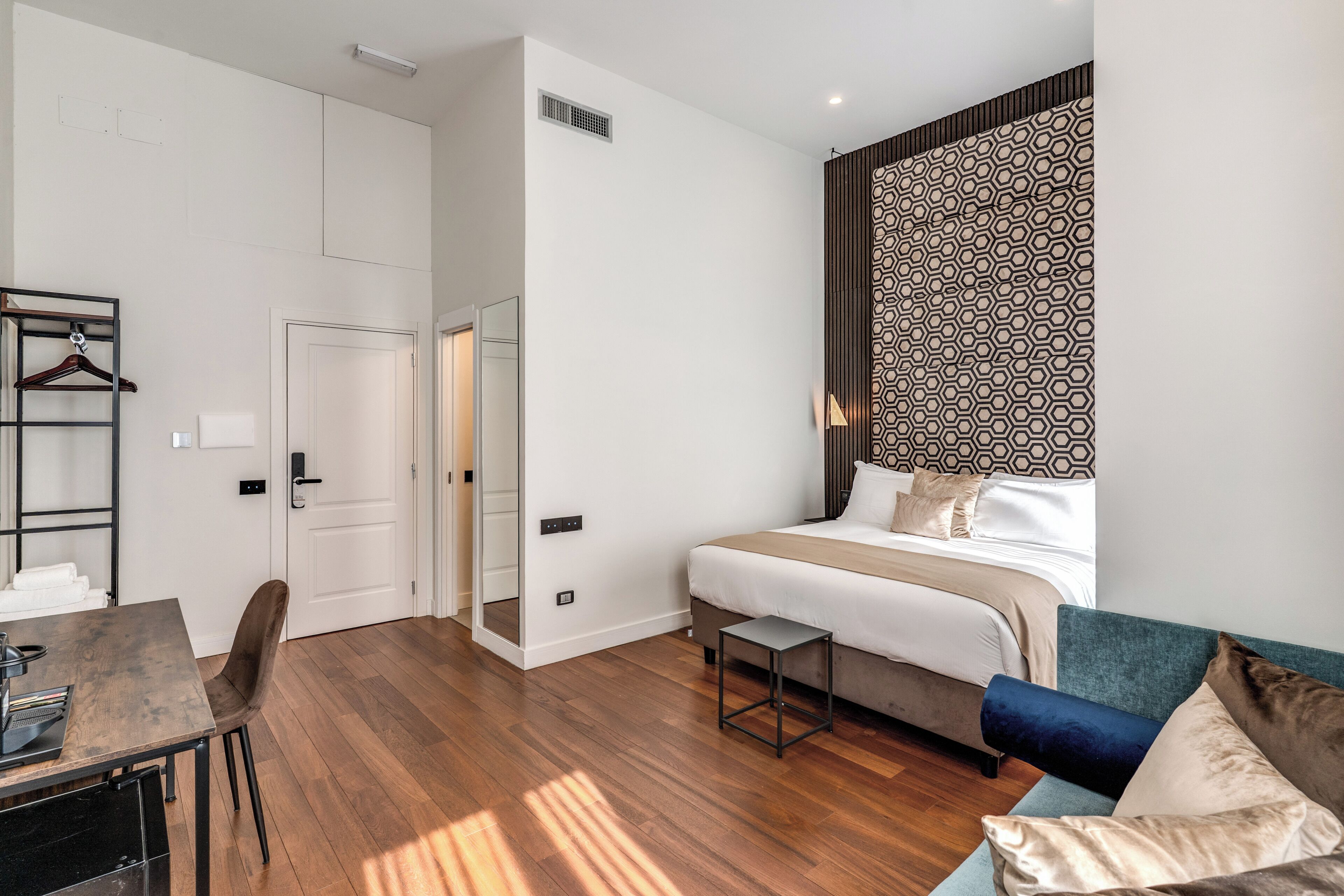 A modern hotel room with a bed, a small table, a chair, and a sofa.