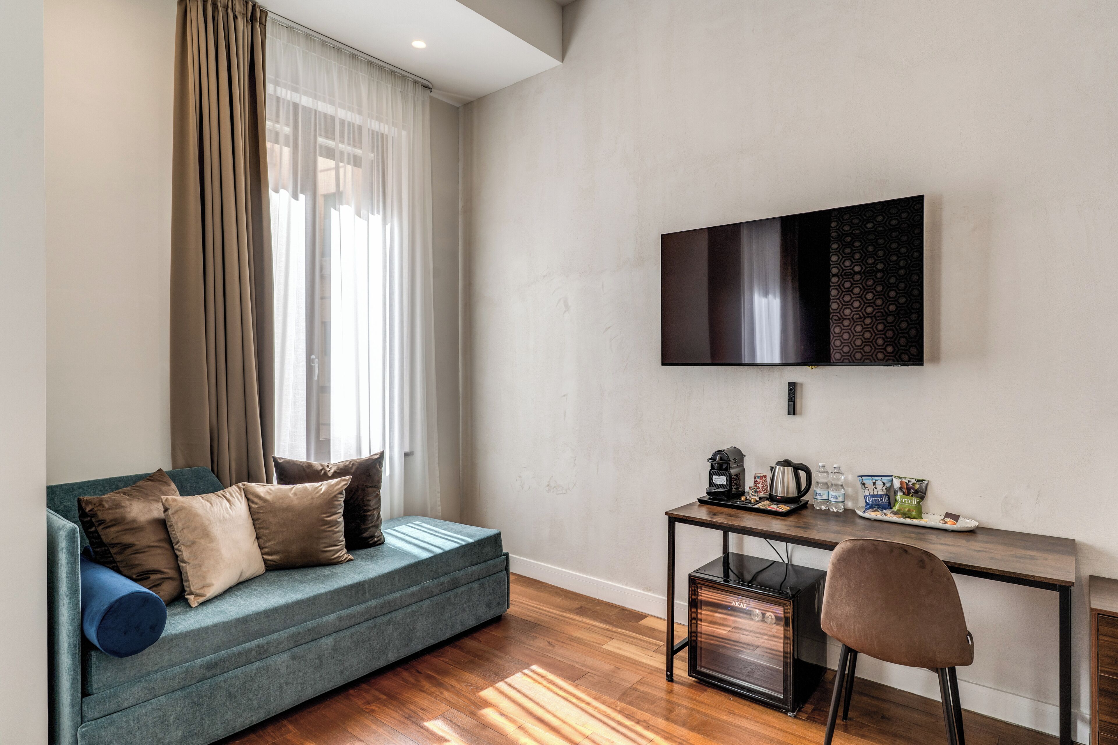 A modern room with a sofa, a desk, a chair, and a flat-screen TV.