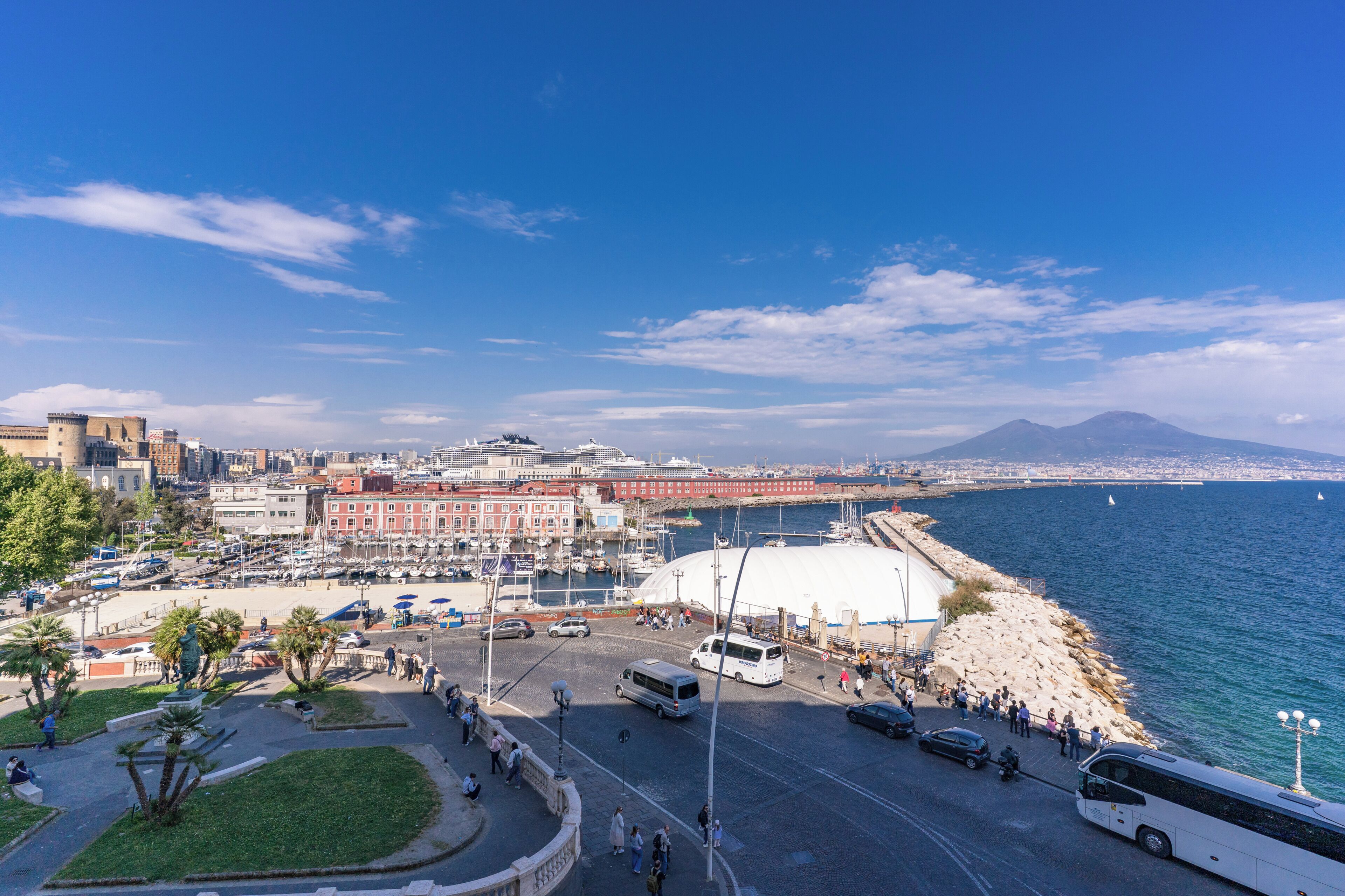A coastal cityscape with a marina, buildings, and a clear blue sky.