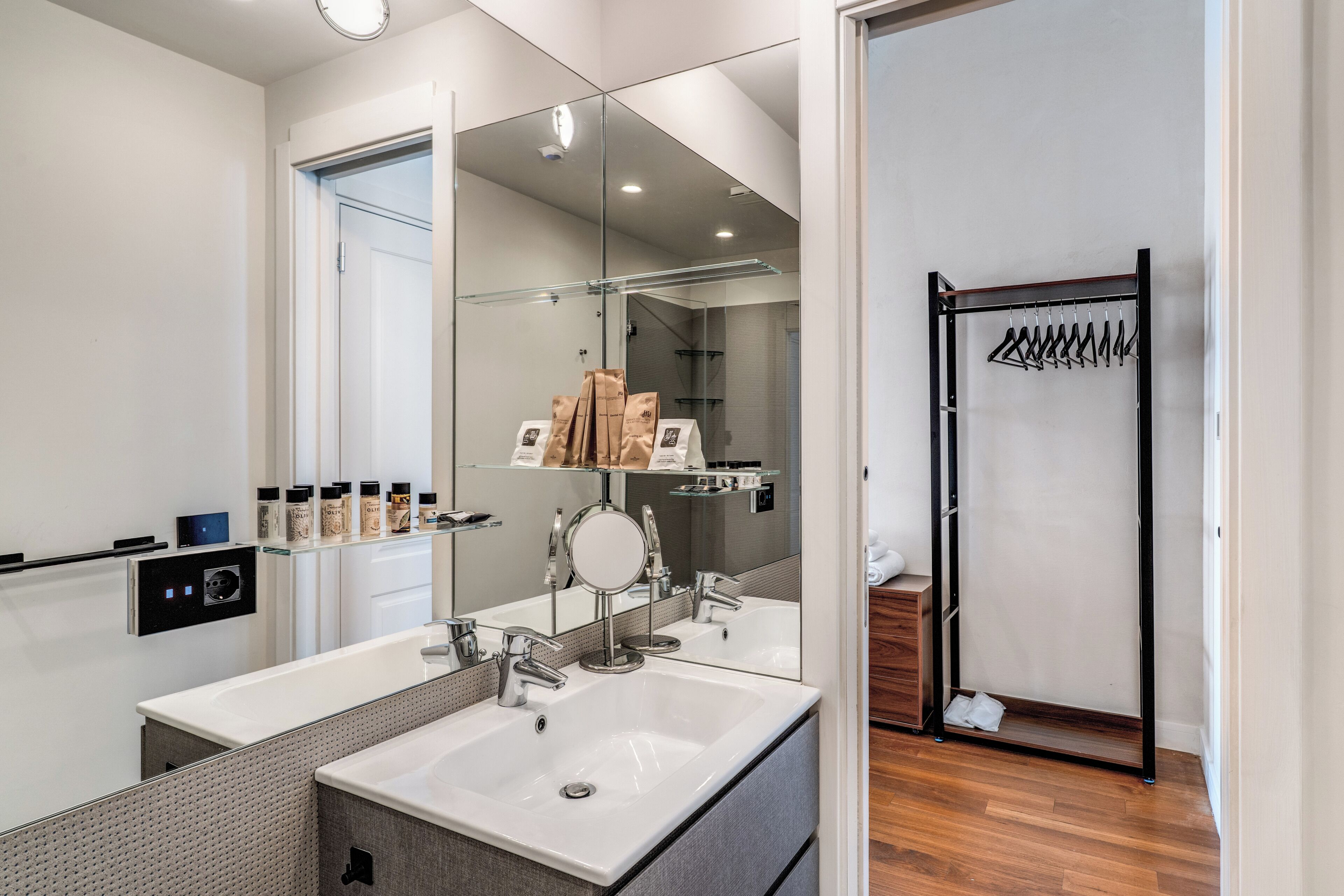 Une salle de bain moderne avec un grand miroir, un lavabo et un espace douche.