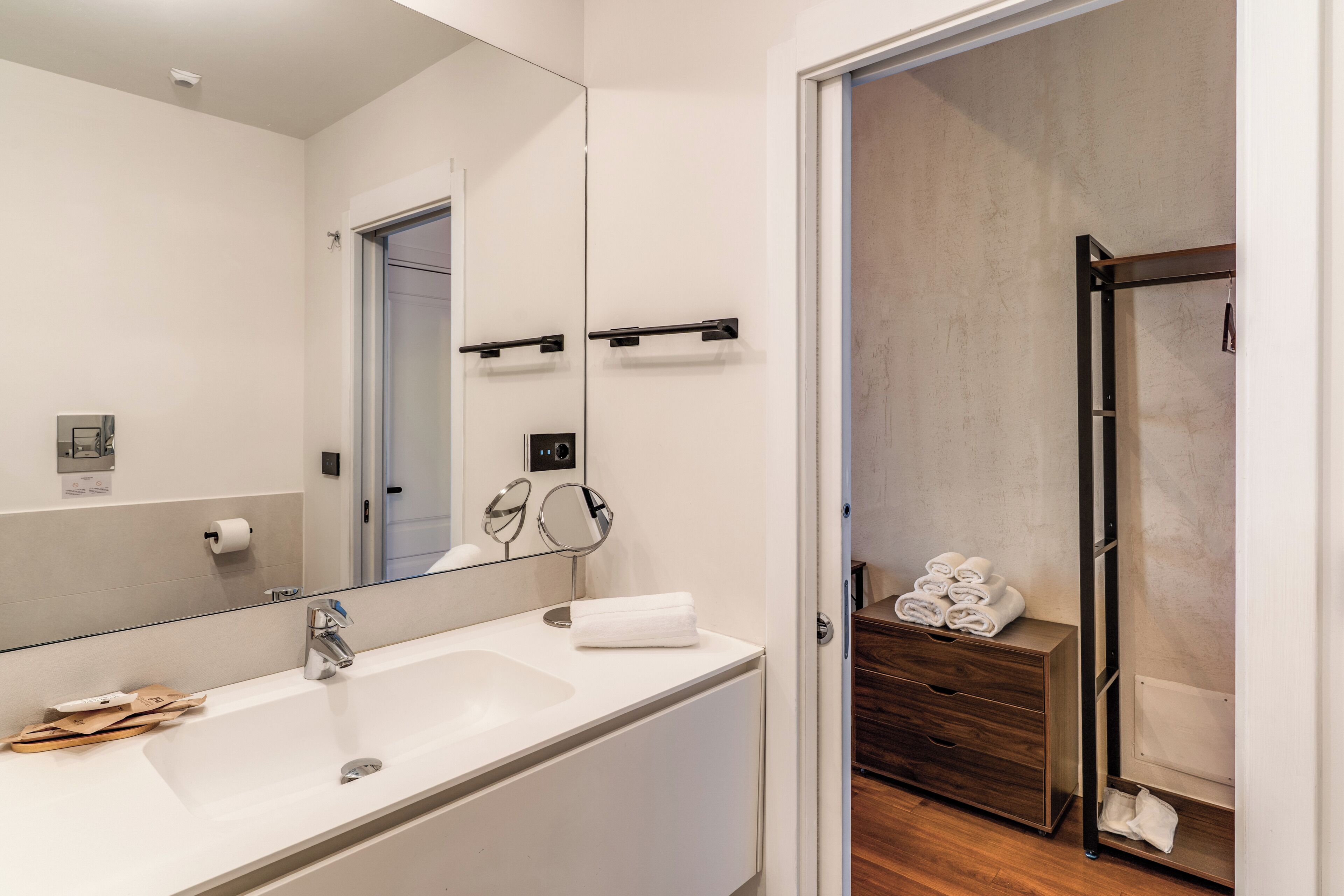 Une salle de bain moderne avec un grand miroir, un lavabo blanc et un meuble-lavabo en bois.
