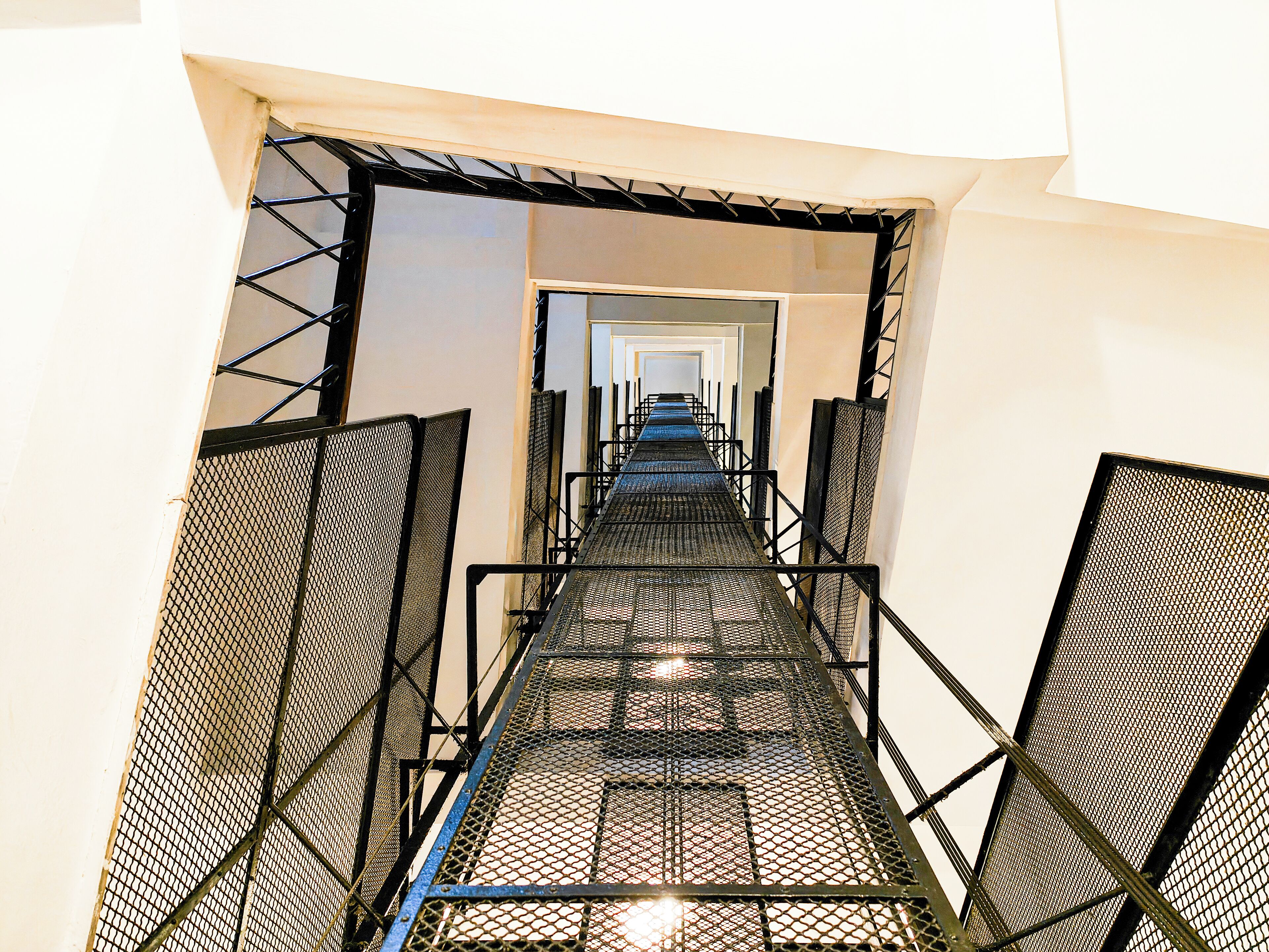 Una escala metàl·lica amb terra de malla que condueix a una porta.